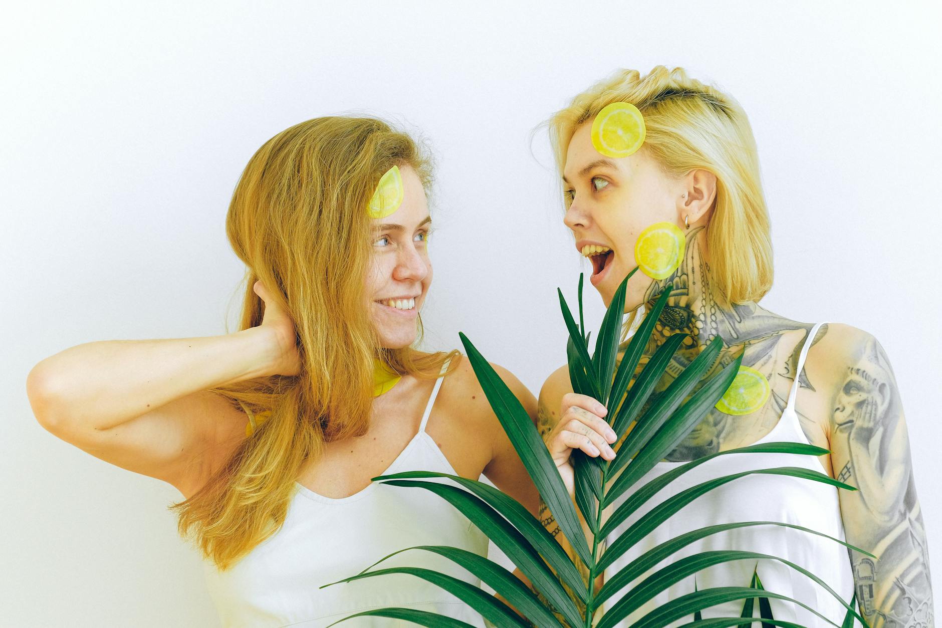 Two women smiling and laughing together with lemon slices, expressing joy and comfort