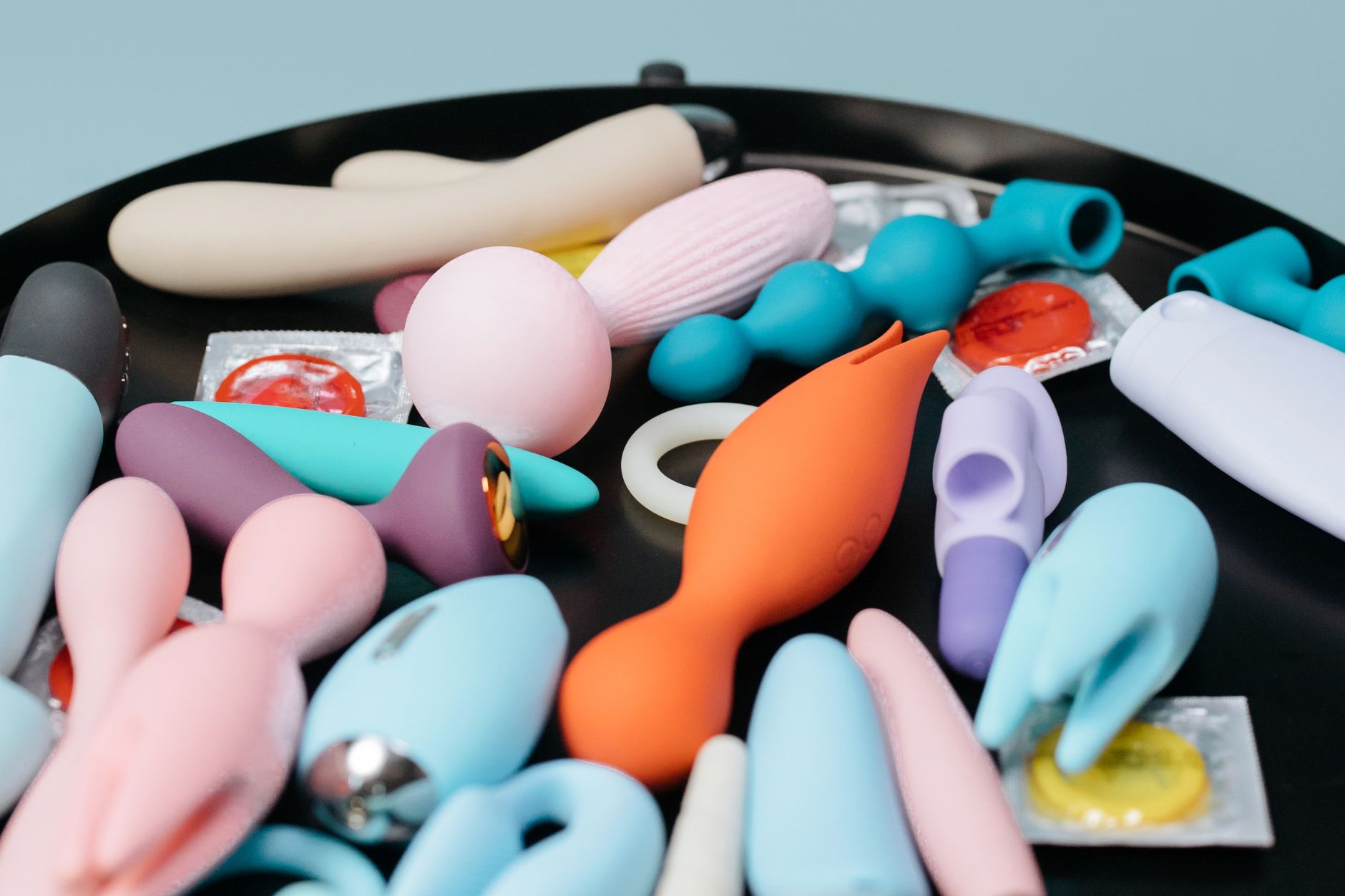 Vibrant collection of sex toys on a black tray, featuring diverse shapes and colors