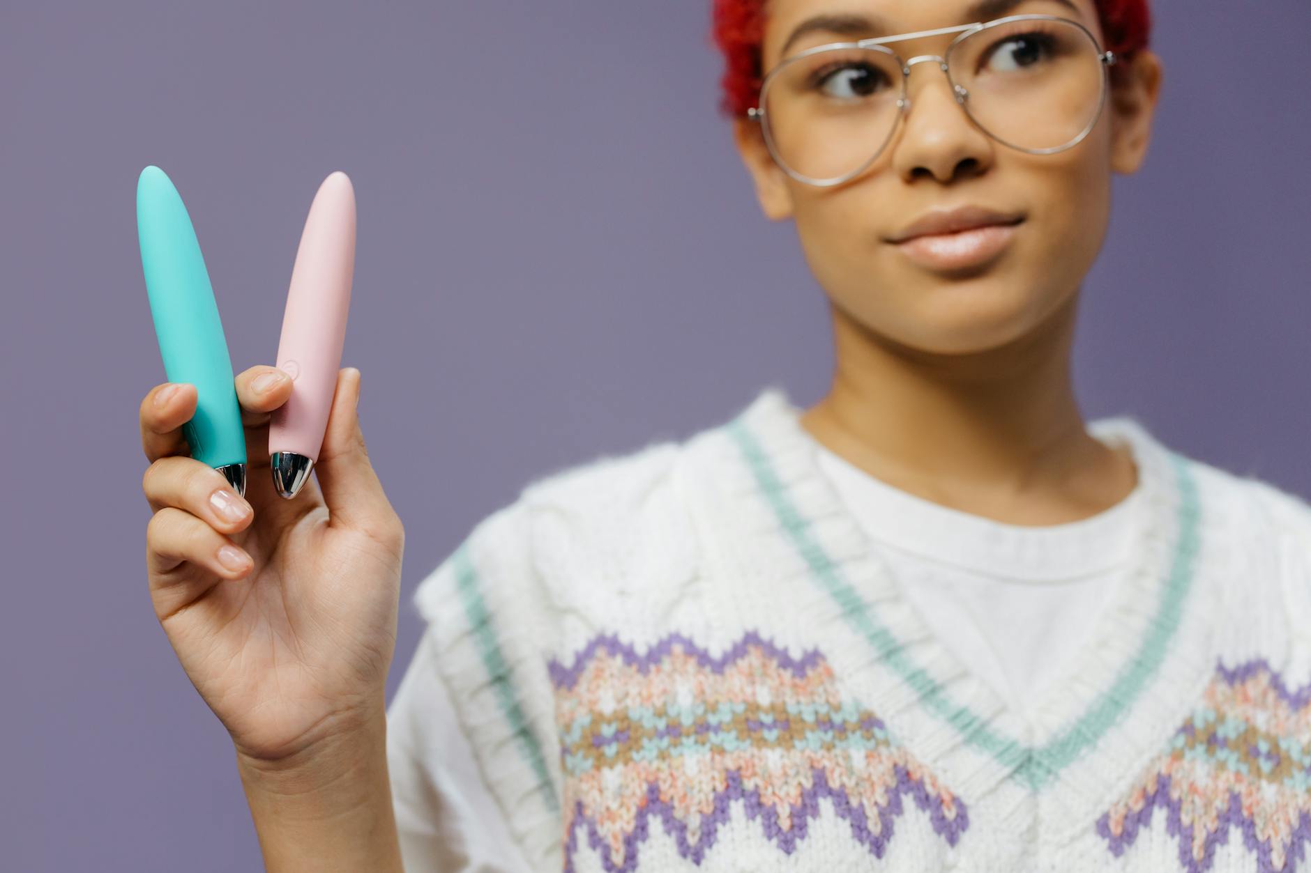 A person holds a colorful vibrator against a purple background, representing modern sexual wellness and pleasure